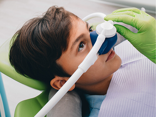 Boy in dental chair wearing nitrous oxide sedation dentistry mask on his nose