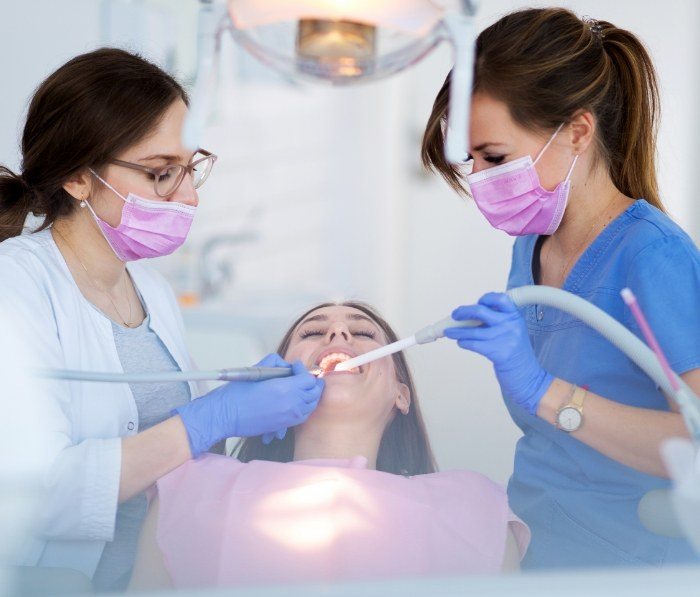 Two dental team members treating a patient